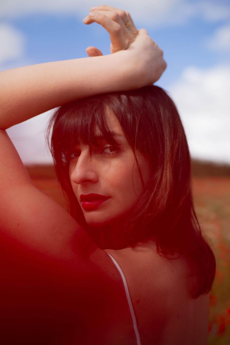 Portrait de Céline Aviani dans un champ de coquelicots flouté en arrière plan